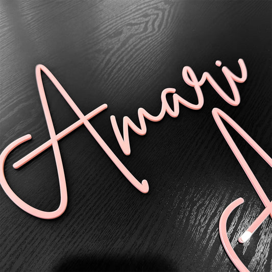 A baby pink acrylic name sign in a single-layer design, featuring the name 'Amari' in pretty pink script lettering.