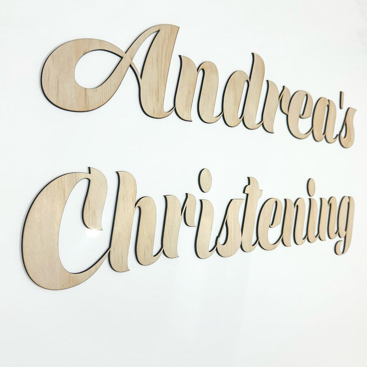 Wooden decorative sign with 'Andrea's Christening' text on a white background