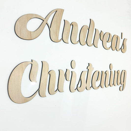 Wooden decorative sign with 'Andrea's Christening' text on a white background